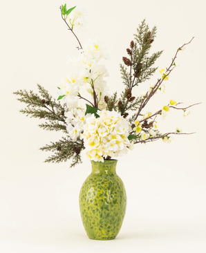 The Earthlight silk artificial flower bouquet is arranged in a green textured vase, with white hydrangeas, delicate white blossoms and green-brown foliage against a plain light background.