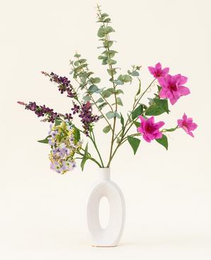 Arranged in a modern white vase, the Lavender Skies silk artificial flower bouquet features pink and purple artificial flowers, yellow accents and lush green foliage - beautiful against a plain light background.