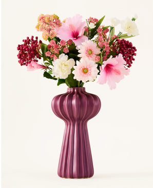 A bouquet of artificial flowers from Zijden, 'Bloom & Berry', with pink, white and red artificial flowers, is beautifully arranged in a tall, ribbed, purple vase against a plain white background.
