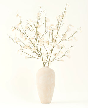 The Silk artificial flower bouquet Eucalyptus cream in a tall, light beige ceramic vase with transparent white leaves creates a serene atmosphere in any artificial flower interior against a light background.