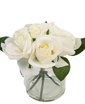 The Artificial Rose Bouquet Real Touch White 18cm is a small clear glass vase with realistic white roses and green leaves, against a plain white background.