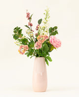 Een roze vaas van keramiek toont het Zijden kunstbloemen boeket Daisy Charm, met verschillende bloemen en groen - roze rozen, witte bloesems en rode bessen - prachtig gerangschikt tegen een effen lichte achtergrond.