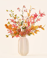 Artificial silk flower bouquet 'Autumn Breeze' in a white ceramic vase, with an arrangement of autumn leaves, small green berries, pink flowers and white flowers, made from high-quality silk flowers. Placed against a light background – the perfect artificial flower bouquet to give any room a long-lasting seasonal atmosphere.