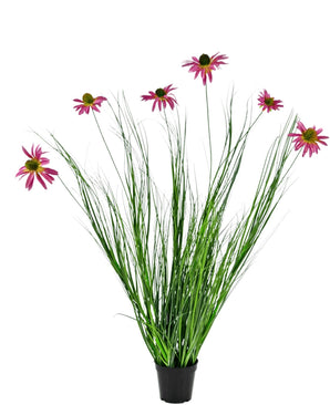 De Kunst Grasplant Chrysant 100 cm brandvertragend is een potplant met lange groene bladeren en lange stelen met daarop felroze margrietachtige bloemen, tegen een witte achtergrond.