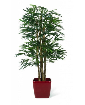 De Kunstplant Lady Palm 180 cm brandvertragend is een hoge kunstpalm met slanke groene stelen en lange, smalle bladeren, weergegeven in een glanzend rode vierkante plantenbak tegen een witte achtergrond.