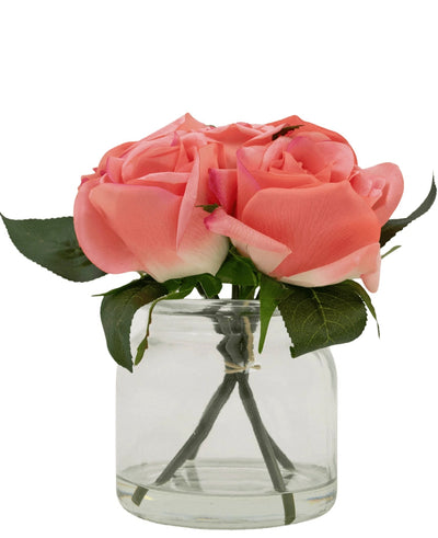 The Artificial Rose Bouquet Real Touch Pink 18cm has four pink artificial roses with green leaves, arranged in a small glass jar and against a white background.
