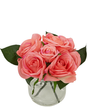 De Kunstrozenboeket Real Touch Roze 18cm heeft vijf roze kunstrozen met groene bladeren, dicht op elkaar in een kleine glazen vaas met water, tegen een witte achtergrond.