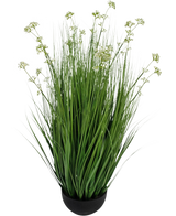De Kunstgras Prei Bloem Ui Graspot 100cm brandvertragend is een kunstgrasplant in pot met lange groene sprieten en kleine witte bloemtrosjes, weergegeven in een ronde zwarte pot tegen een witte achtergrond.