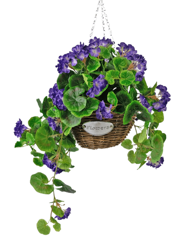 De Kunstbegonia paars in mand UV 70cm is een hangende rieten mand met groene bladeren en levendige paarse bloemen, opgehangen aan een zilveren ketting en voorzien van een klein metalen label met de tekst "Flowers.