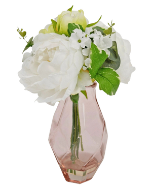 The Artificial Bouquet in Glass 25 cm has a small bouquet of white flowers with green leaves, arranged in a faceted, light pink glass vase.